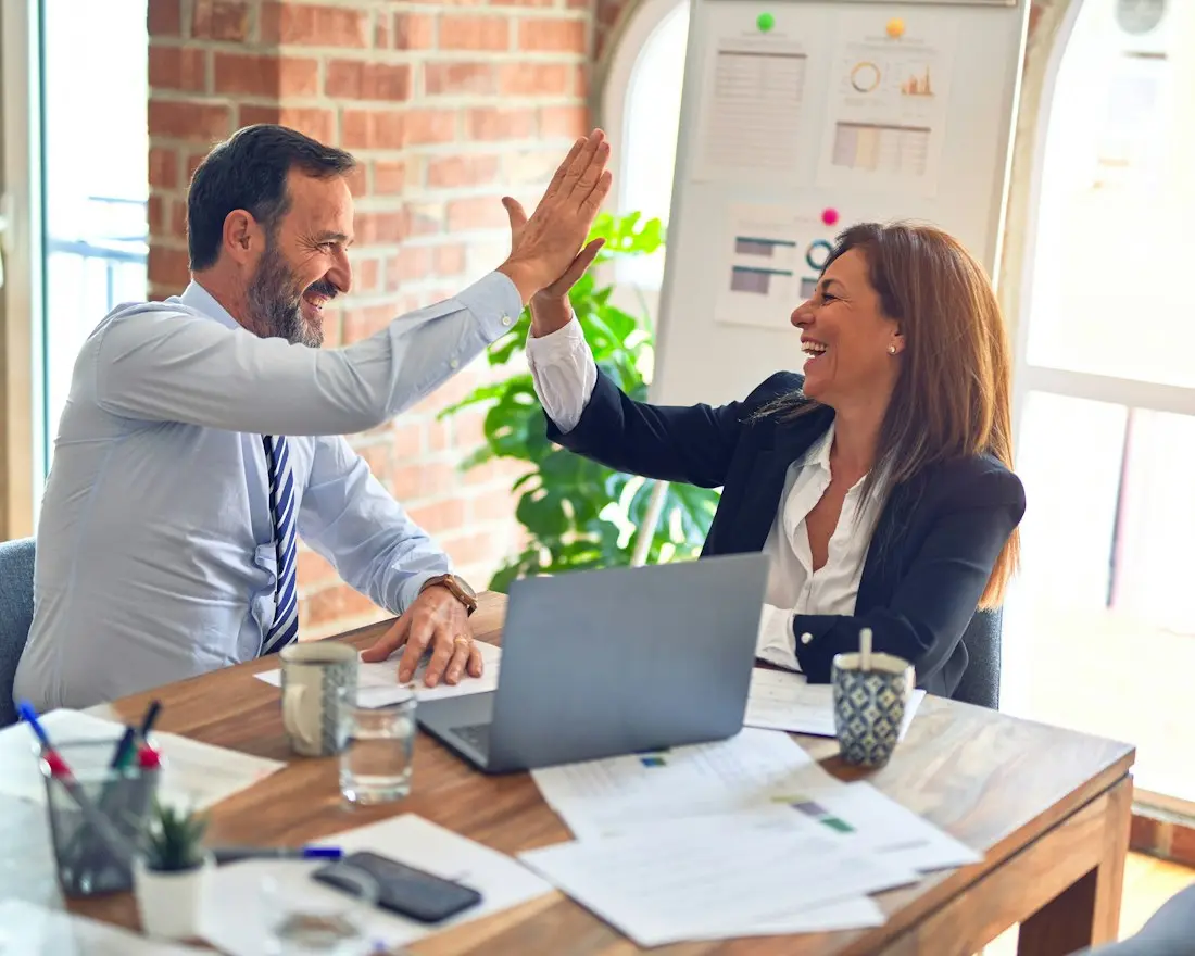 Business partners high-fiving after organizing their operations and funding plan