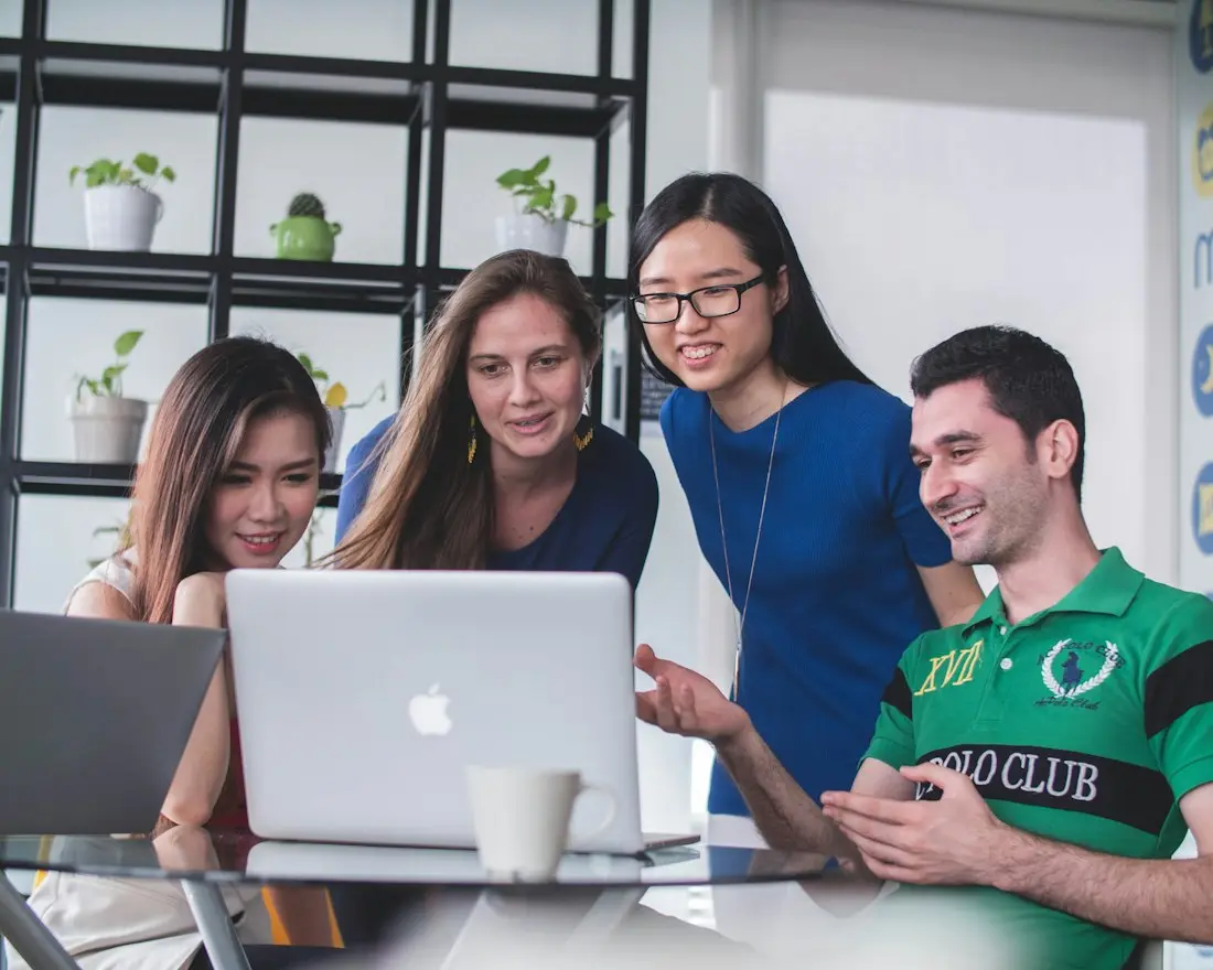 Diverse team of entrepreneurs reviewing business plans together on a laptop